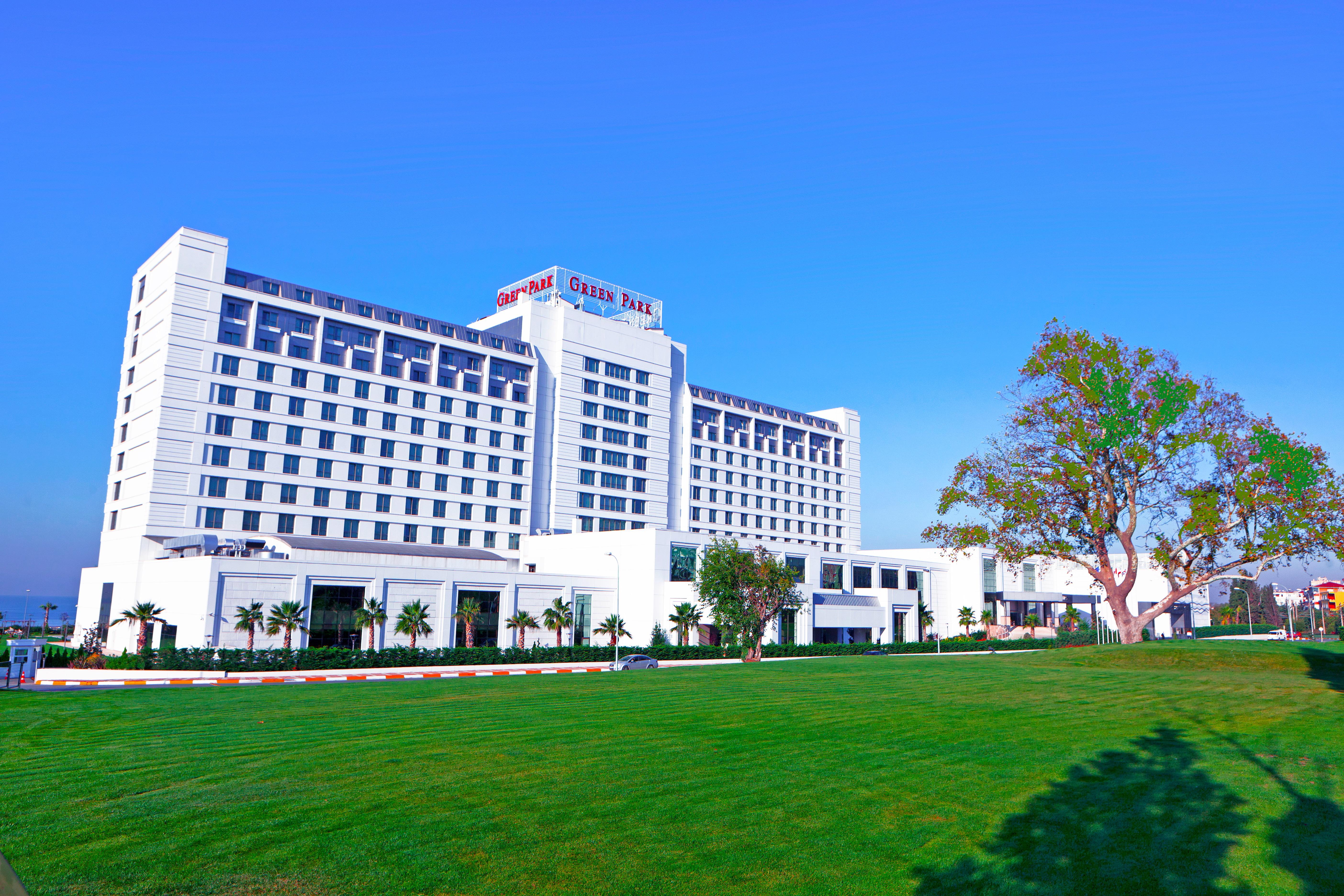 The Green Park Pendik Hotel Istanbul Exterior photo The photo shows a modern multi-story hotel building with a clean, contemporary design. The structure features large windows and a prominent sign at the top indicating its name. In front of the hotel, there is a well-maintained green lawn with some la